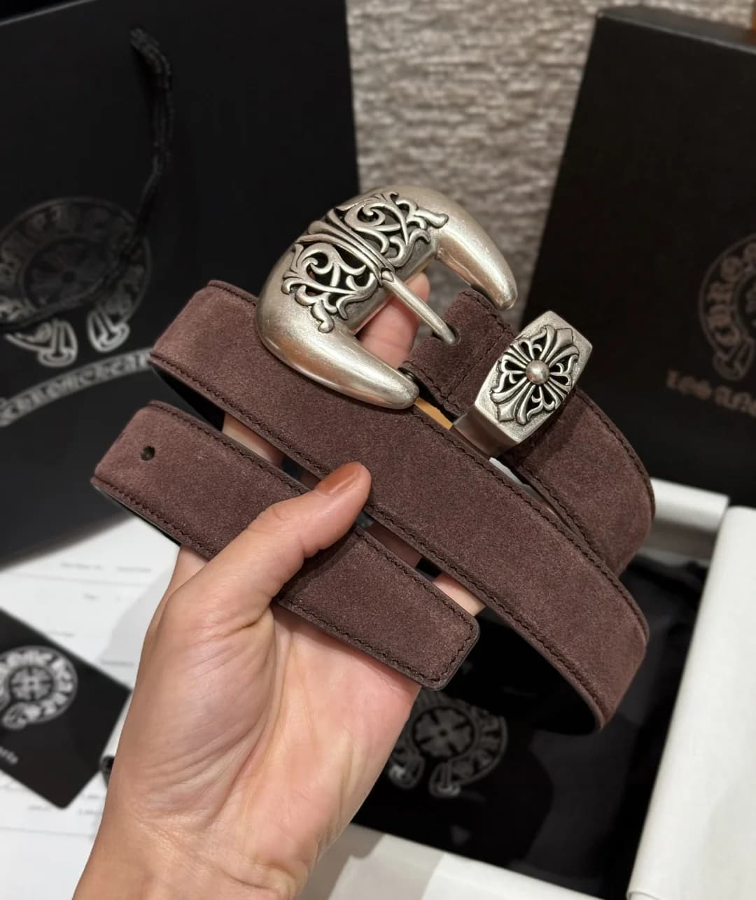 Мужской коричневый ремень Chrome Hearts из замши в сложенном виде в руке