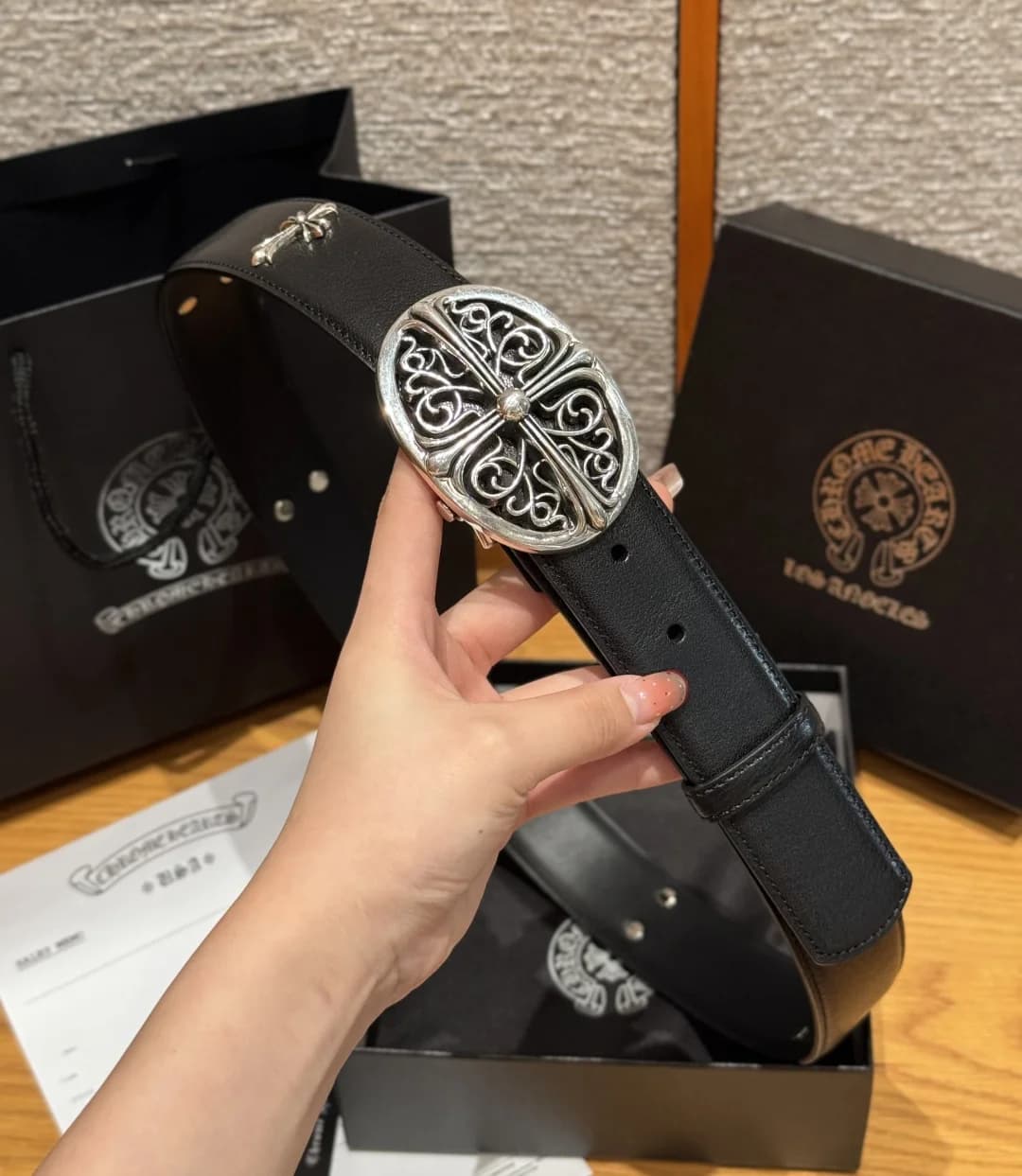 Кожаный ремень Chrome Hearts с ажурной пряжкой Oval Cross в руке