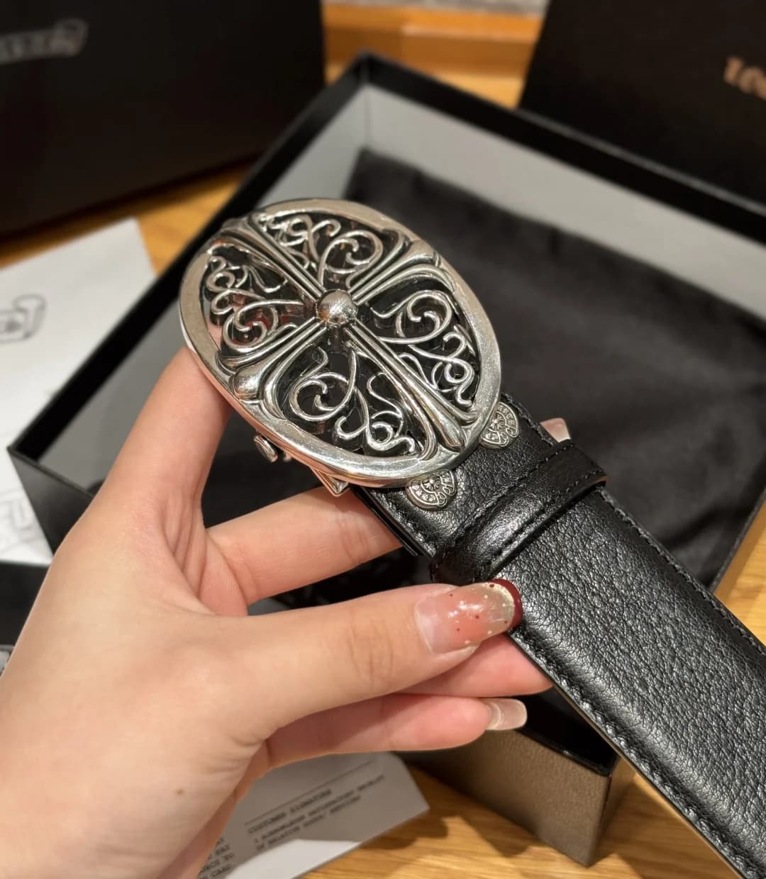 Крупный план массивной серебристой пряжки Chrome Hearts с готическим крестом