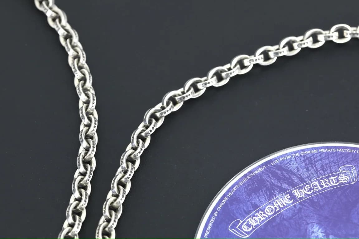 Фрагмент звеньев цепи Chrome Hearts с гравировкой крупным планом