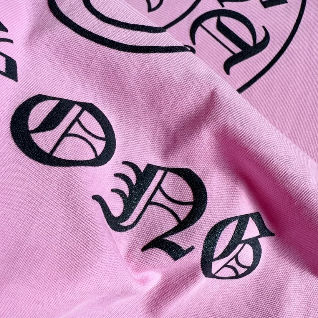 Крупный план текстурированного принта Hong Kong на розовом лонгсливе Chrome Hearts