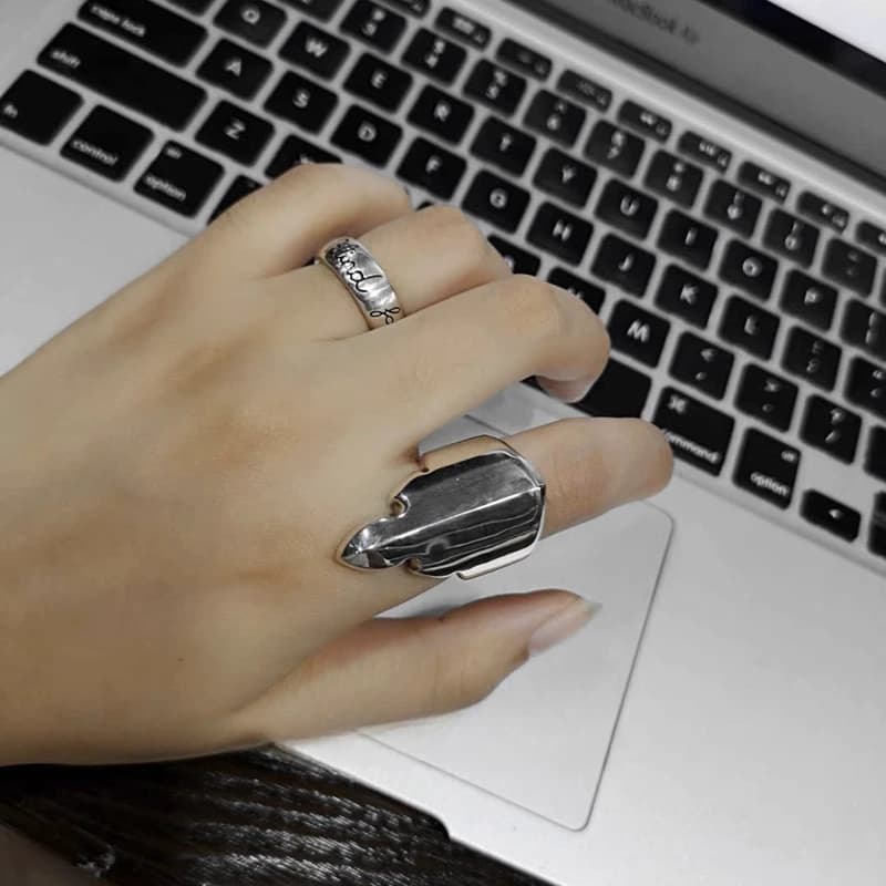 Серебряное кольцо Fleur Tail на руке рядом с клавиатурой ноутбука