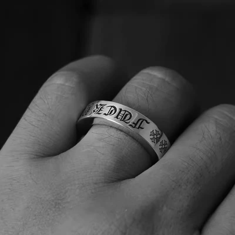 Серебряное кольцо с готической надписью Fuck You на пальце руки, чёрно-белый ракурс