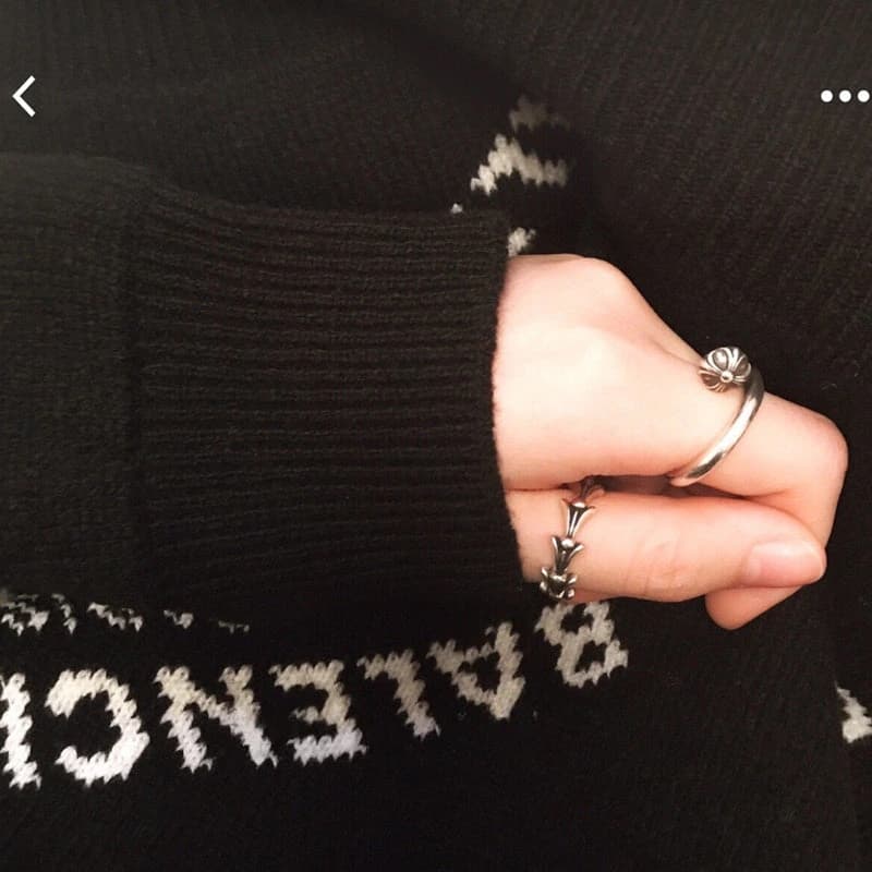 Рука с серебряным кольцом Nail Crossball на фоне черного трикотажа