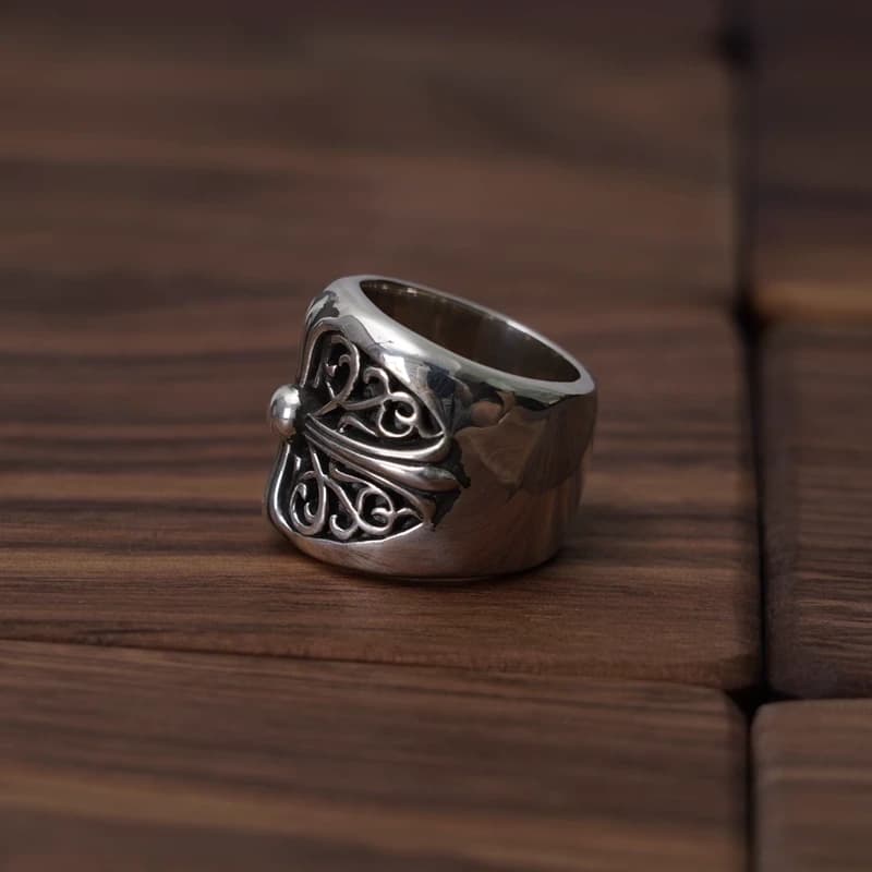 Серебряное кольцо с орнаментом на деревянном фоне, ракурс сбоку