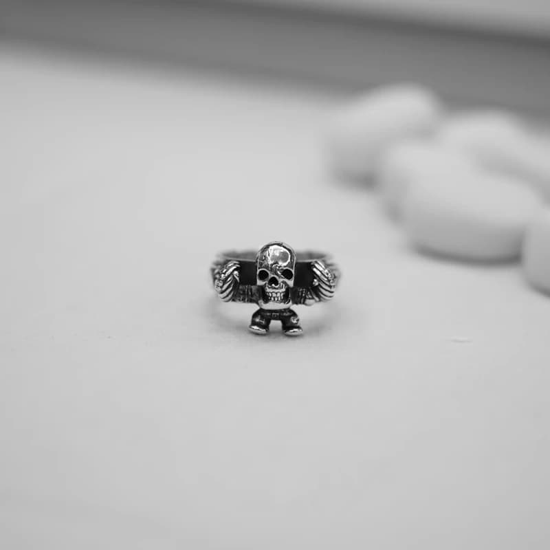 Серебряное кольцо с фигурой скелета на краю белой тарелки
