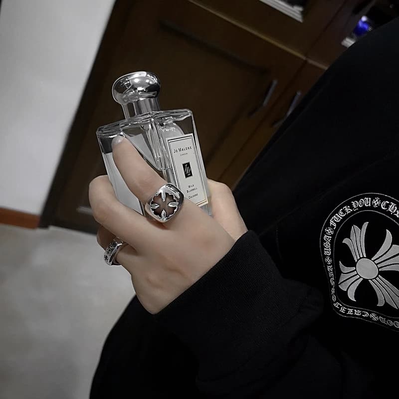 Массивное серебряное кольцо на указательном пальце руки с флаконом парфюма