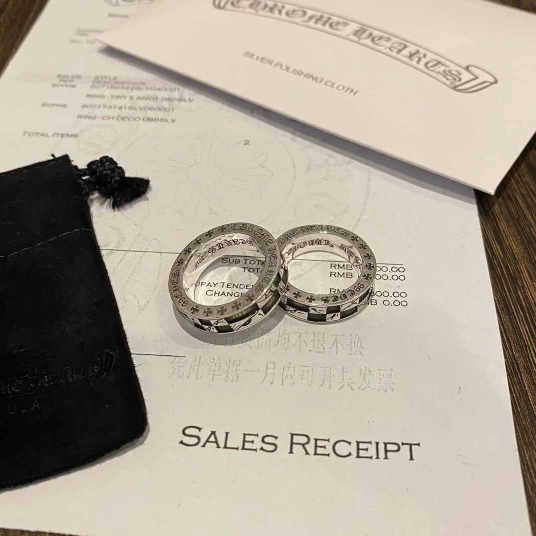 Вид сверху на кольца Chrome Hearts на фоне товарного чека и чехла
