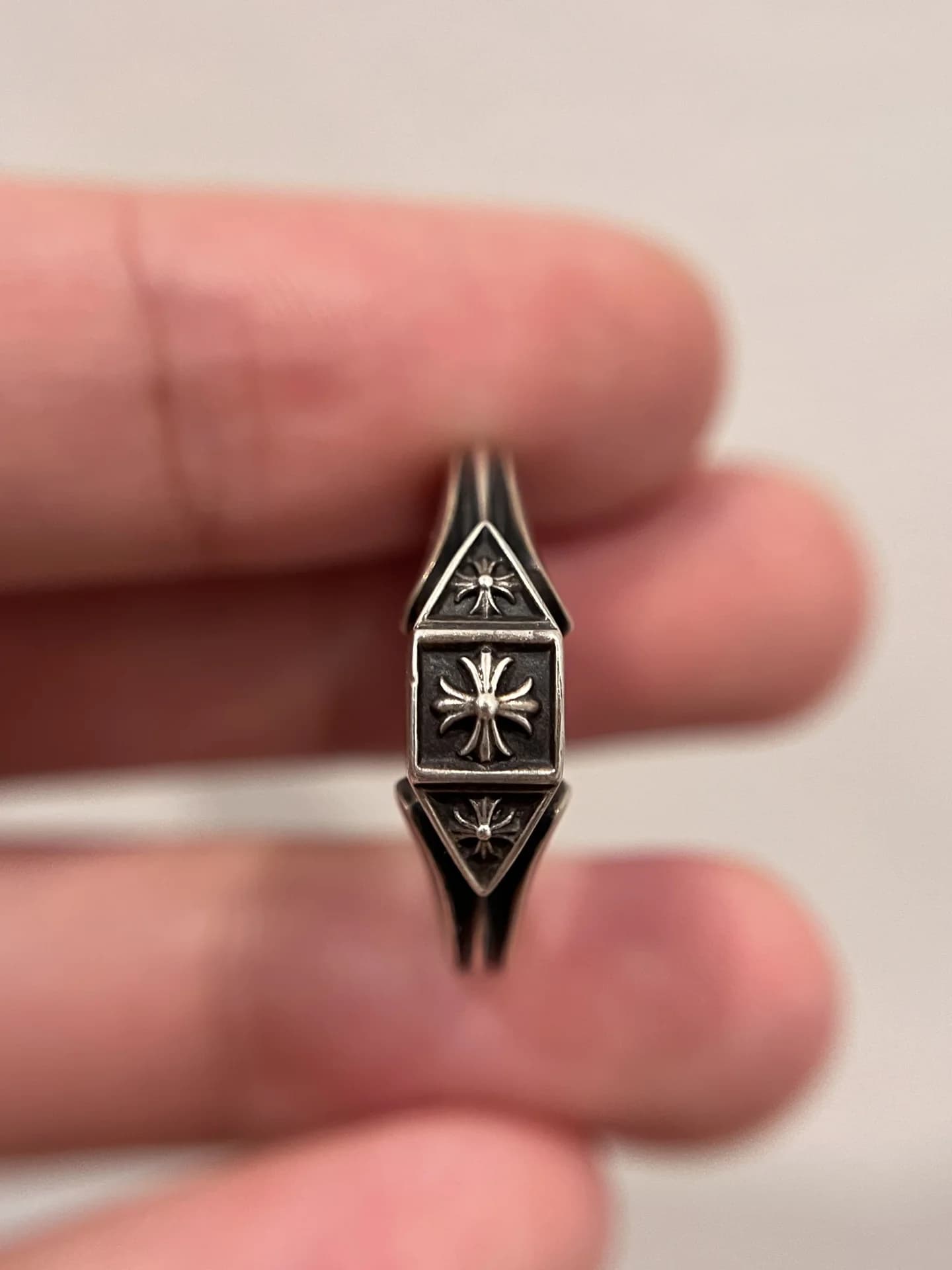 Вид сверху на геометрическую площадку с крестом серебряного кольца Chrome Hearts