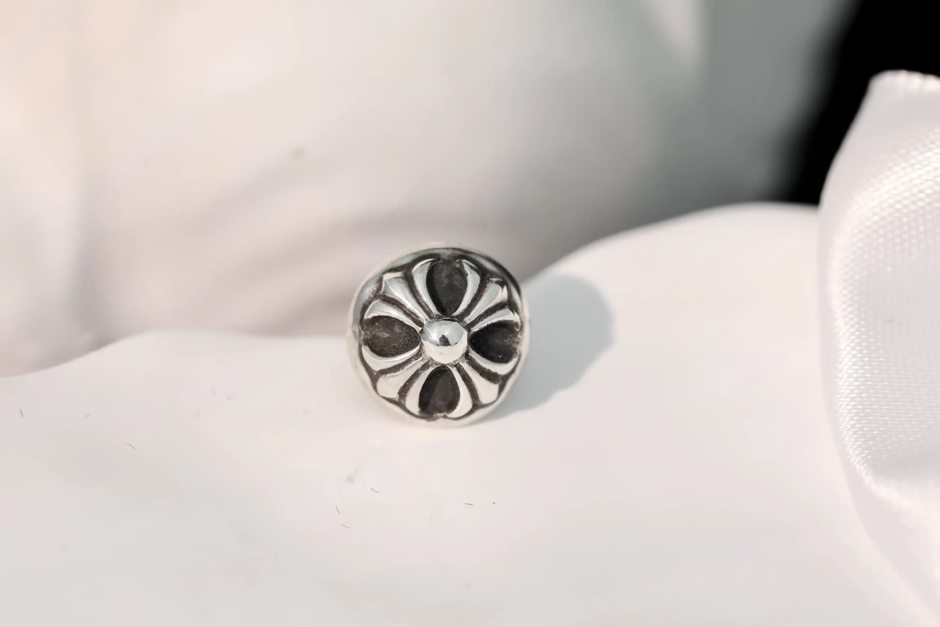 Макрофотография резного цветочного креста на серьге Chrome Hearts