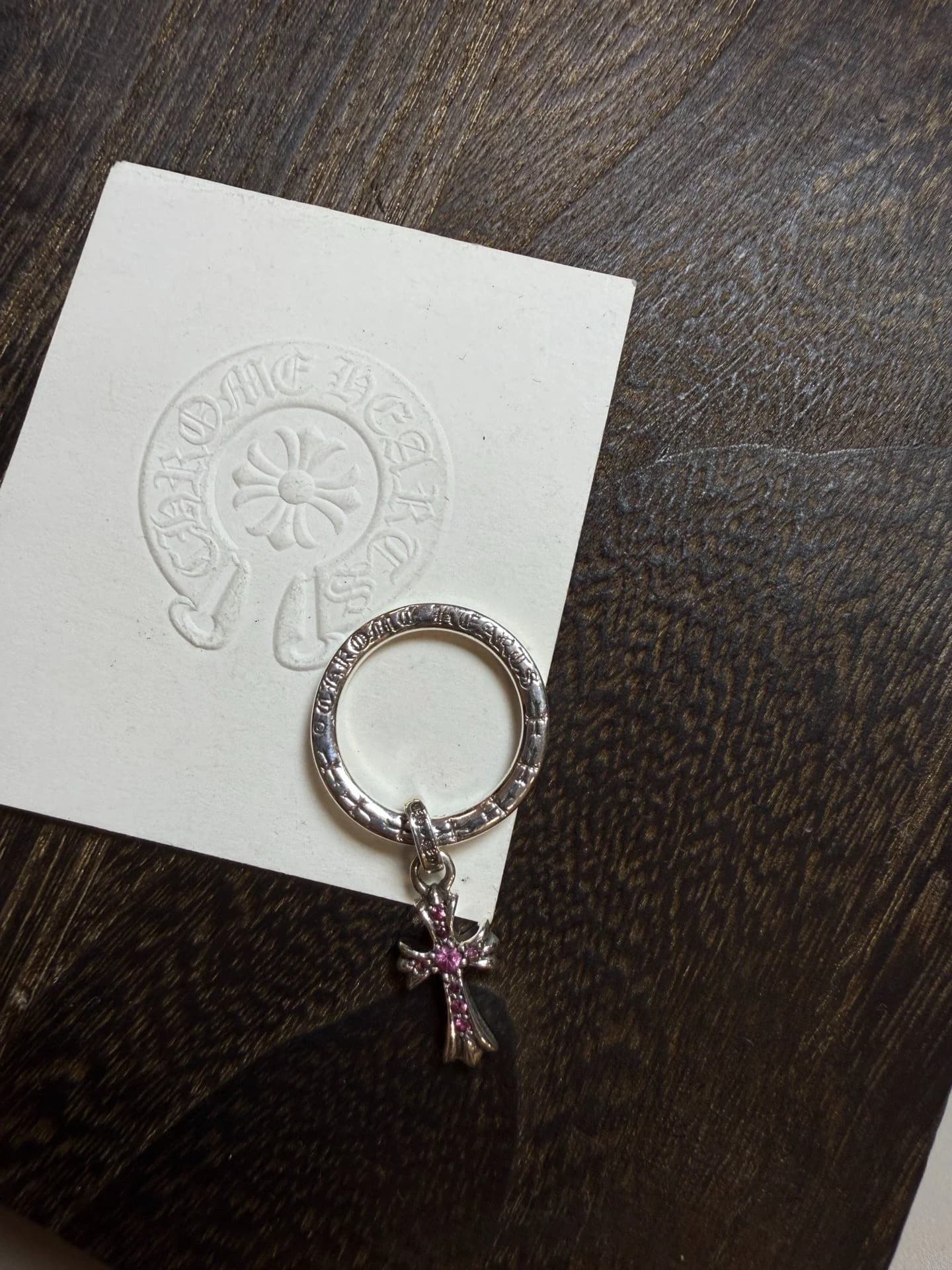 Кольцо Chrome Hearts с подвеской Baby Fat и розовыми камнями на темном деревянном фоне