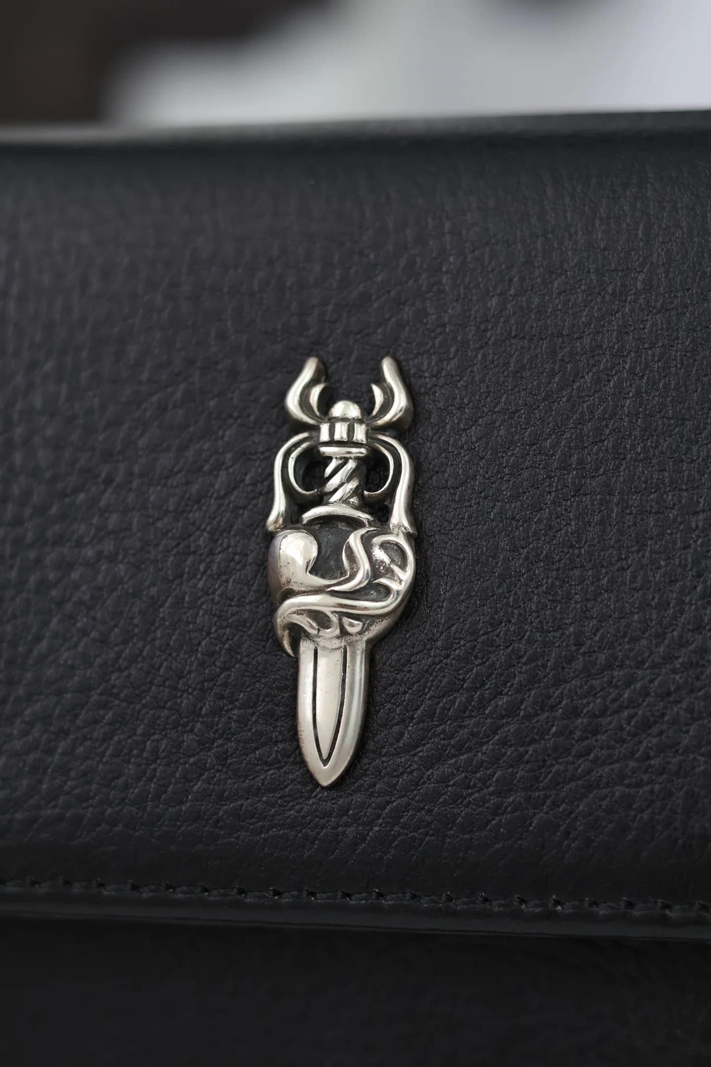 Деталь серебряного декора в виде меча Dagger на черной зернистой коже