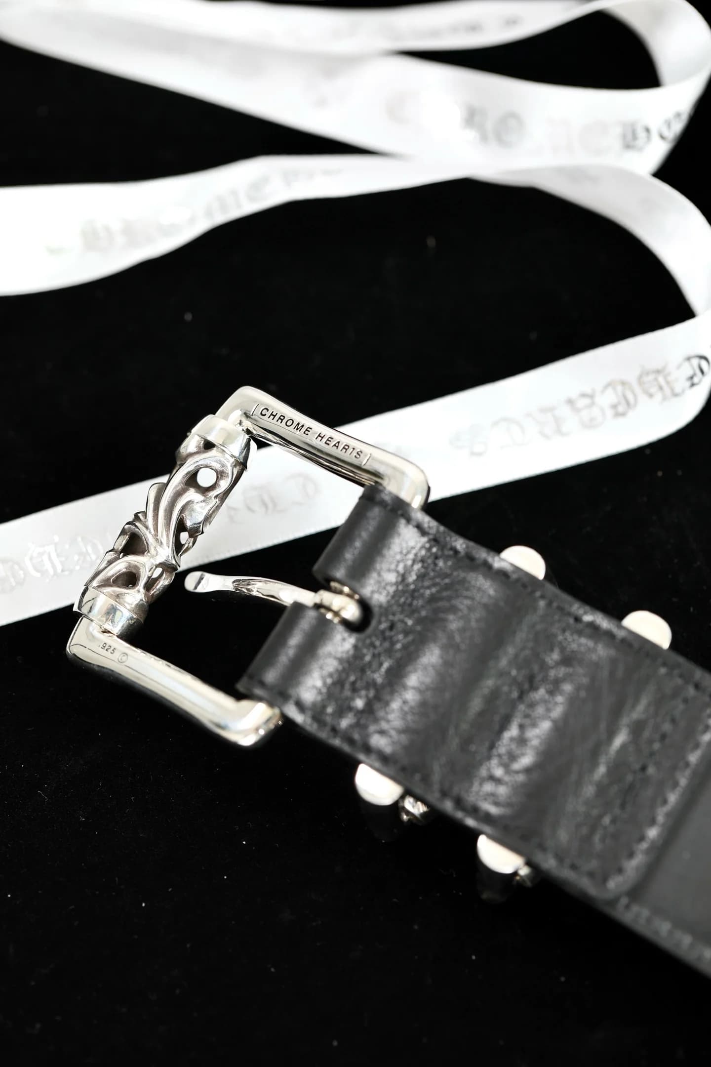 Крупный план серебряной пряжки ремня Chrome Hearts с гравировкой