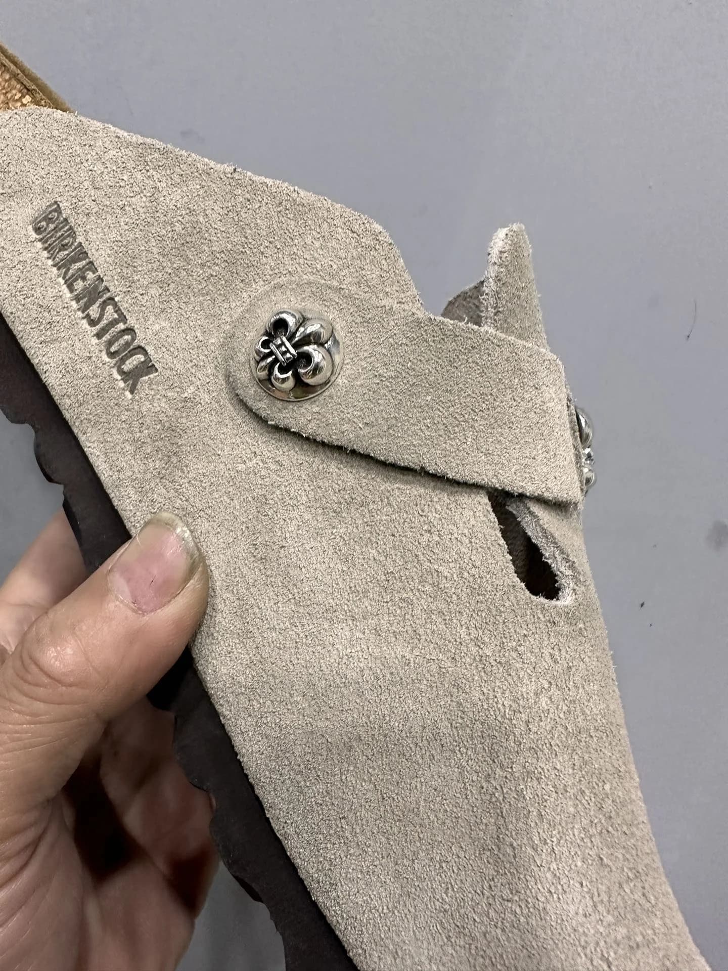 Деталь серебряной фурнитуры в виде лилии на сабо Chrome Hearts