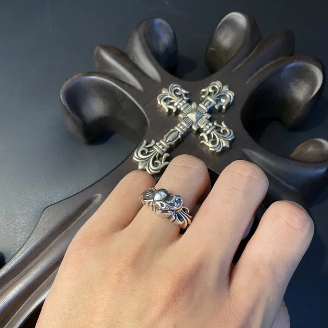 Кольцо Chrome Hearts Floral Heart на руке рядом с декоративным крестом