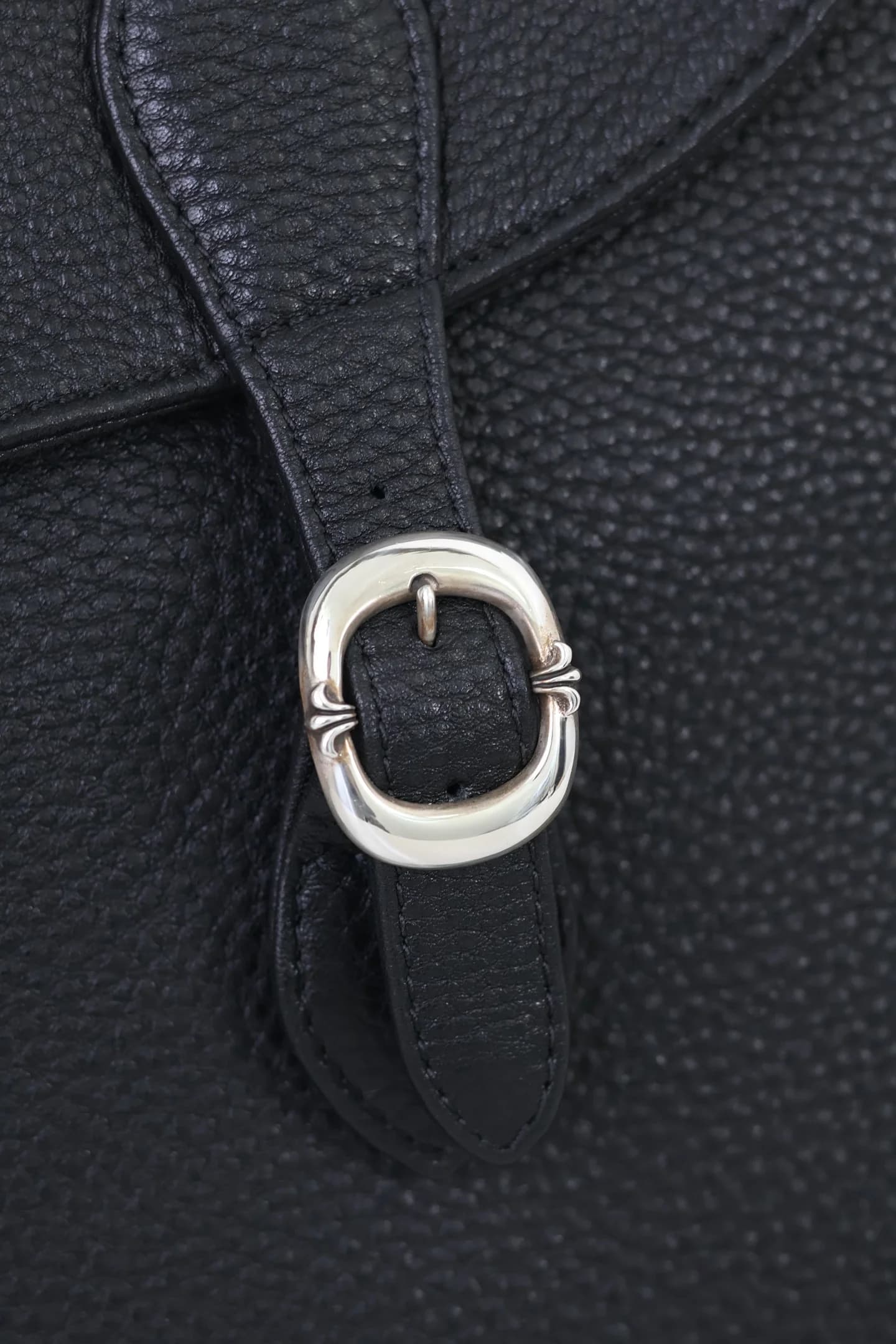 Крупный план серебряной пряжки на ремешке сумки Chrome Hearts